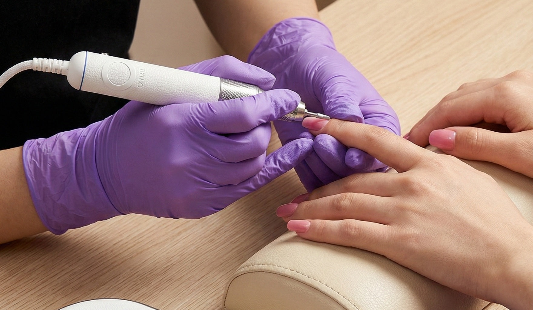 Manicurist demonstrating professional nail drill techniques for precise and safe salon-quality nail care