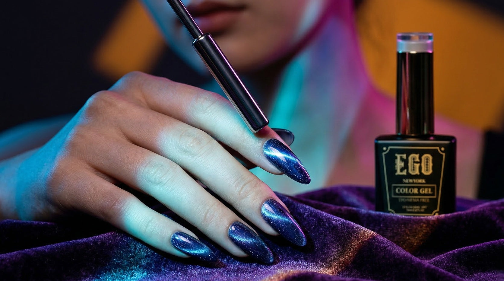 Close-up of shimmering green and blue magnetic cat eye nails next to a "EGO" by Velvet Hands gel polish bottle and magnetic tool.